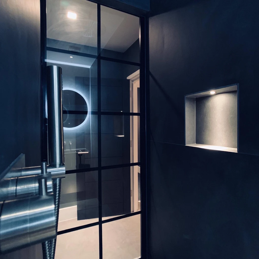 Luxury bathroom featuring a black crittall-style shower screen, illuminated recessed niche, LED mirror and contemporary dark porcelain tiles