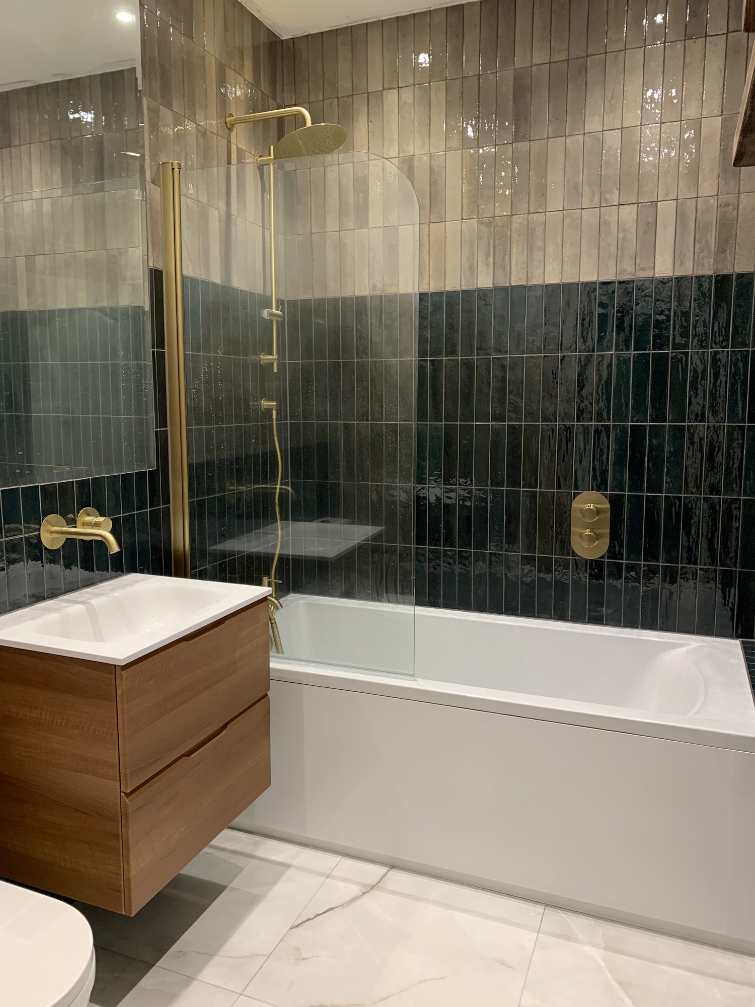 Home Luxury bathroom featuring brushed brass shower and taps, floating walnut vanity unit, feature wall tiles and modern bath installed by JD Designed Bathrooms