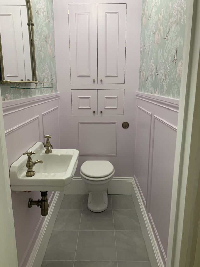 Traditional cloakroom renovation featuring wall panelling, decorative wallpaper, Victorian style basin, concealed storage cupboards and grey floor tiles installed by JD Designed Bathrooms