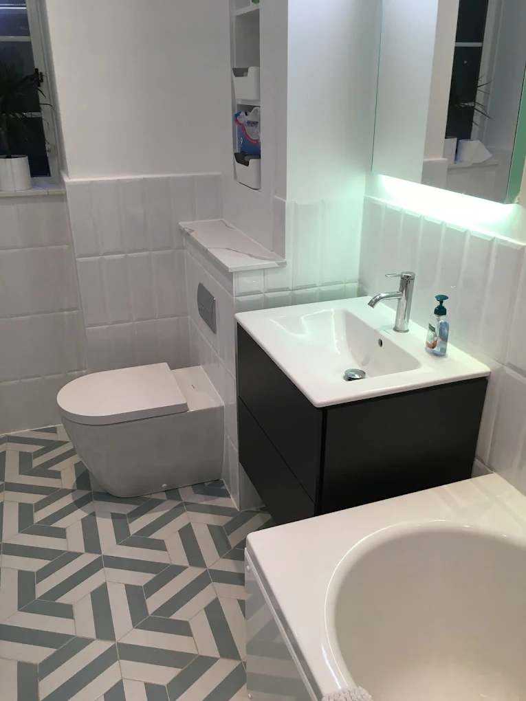 Modern family bathroom with geometric floor tiles, back to wall toilet, floating vanity unit and illuminated mirror cabinet.