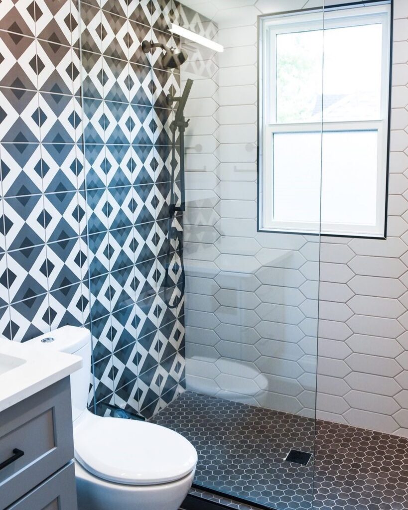 Modern walk-in shower with level-access tiled floor, glass screen and hexagon wall tiles in a contemporary bathroom